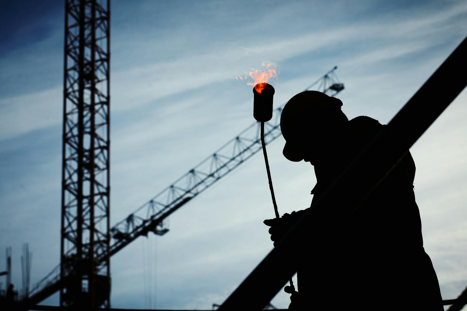 A worker and crane silhouetted against the sky